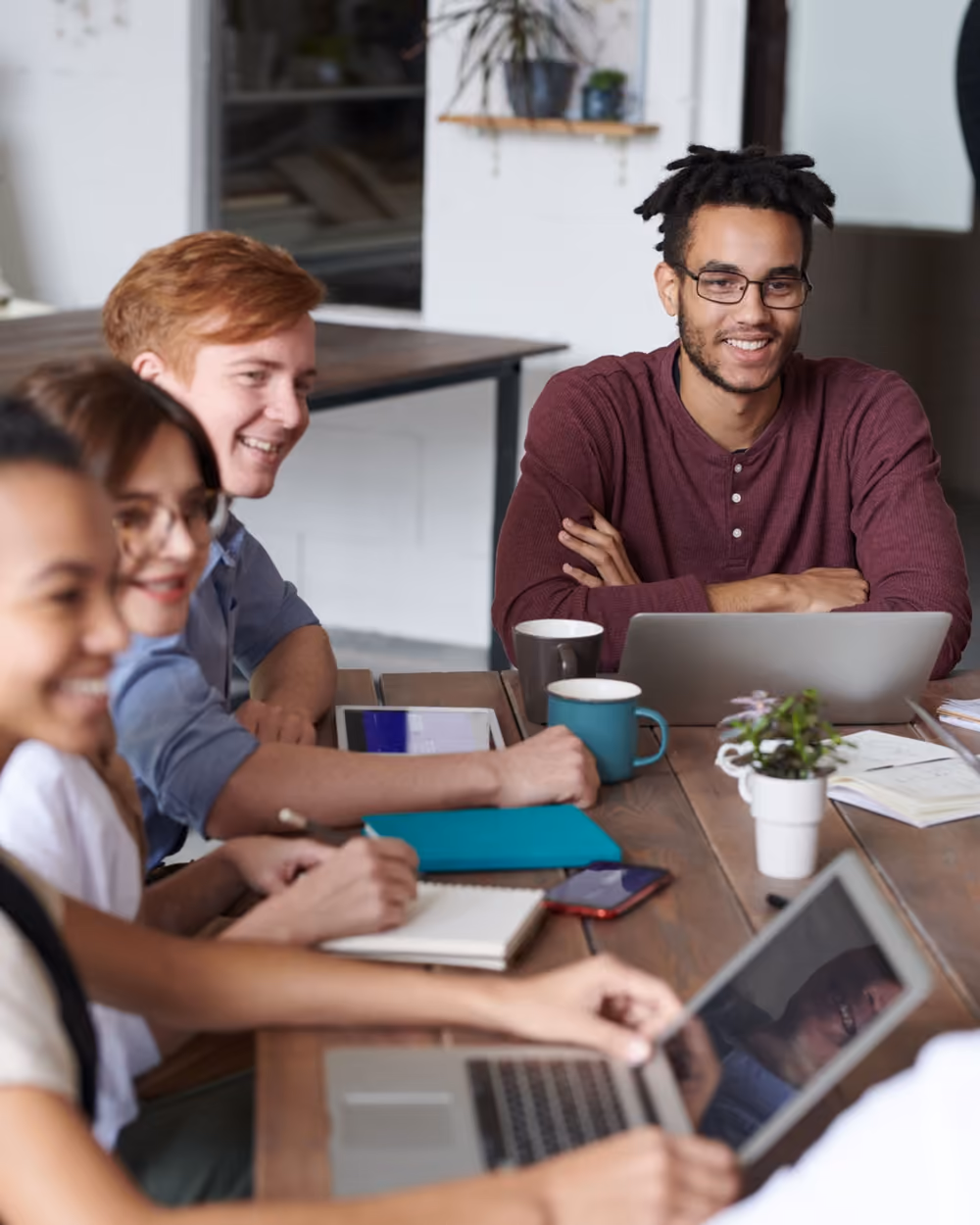 A small team smiling during a meeting at a shared table